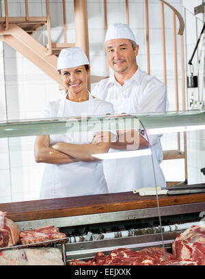 Confident Butchers Standing At Meat Counter Stock Photo