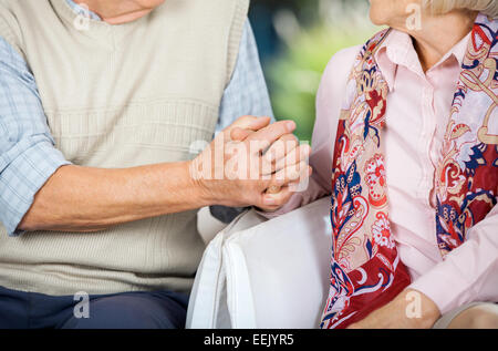 Senior Couple Holding Hands While Sitting On Chairs Stock Photo