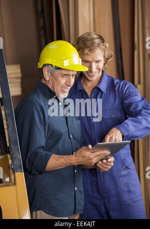 Carpenters Using Tablet Computer In Workshop Stock Photo
