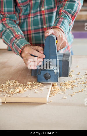 Carpenter Using Electric Planer On Plank Stock Photo
