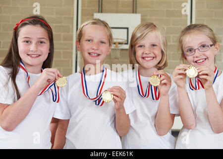 Female School Sports Team In Gym With Medals Stock Photo