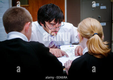 Teacher helping students with their work in classroom Stock Photo