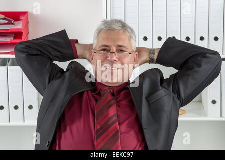 Mann mittleren Alters sitzt im Büro und relext, Middle-aged man sitting in an office, relaxing