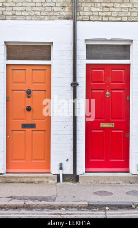 Red and orange front doors on adjoining terraced homes in the UK Stock Photo