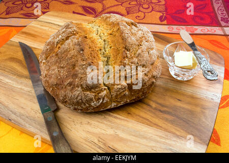 Loaf of freshly baked  Soda Bread  on a cutting board with a dish of butter Stock Photo