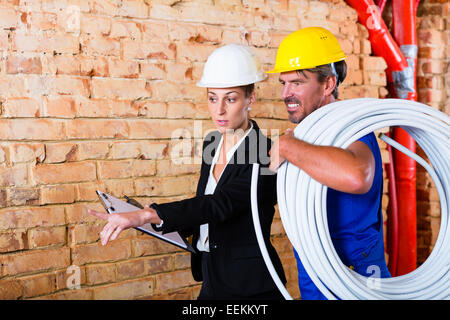 Builder and architect working on construction site discussing things still to do Stock Photo