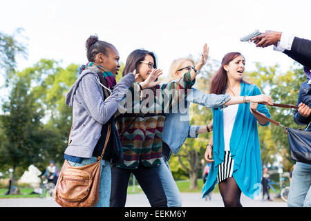 Group of girls being threatened with gun by armed robber Stock Photo