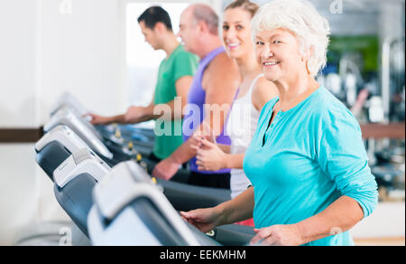 Group with senior and young men and women people on treadmill in fitness gym running for sport Stock Photo
