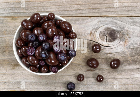 Overhead shot of dark chocolate and blueberries in white bowl on rustic wood Stock Photo