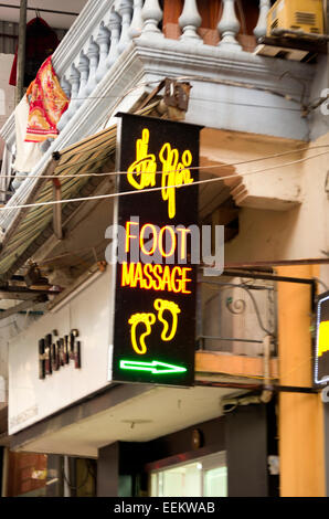 'Foot Massage' sign, yellow neon letters, hangs off balcony. Stock Photo