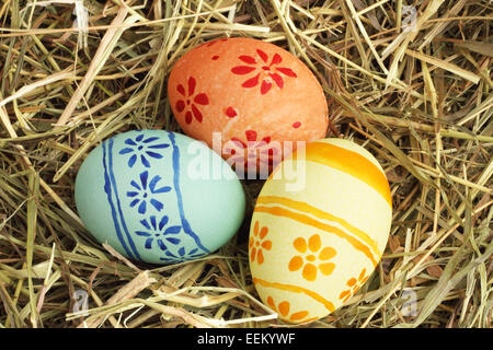 Three colored Easter eggs on hay at sunny day Stock Photo