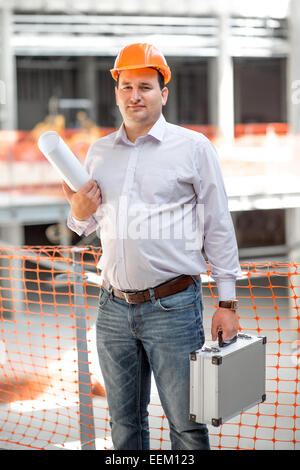 A foreman with drawings and case supervising the project at the construction. Stock Photo