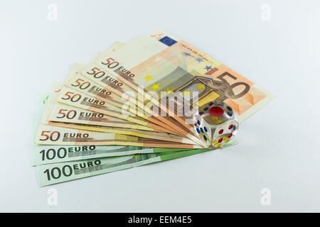 Transparent dice over a series of Euro bills as a concept of gambling with money and engaging in high risk investments , on whit Stock Photo