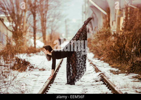 Dancer striking a pose on railway tracks in winter Stock Photo