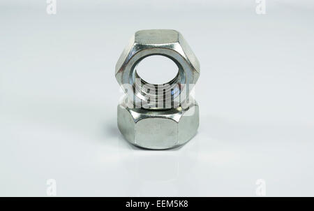 Two big, metallic nuts one placed on top of the other, isolated on white background Stock Photo