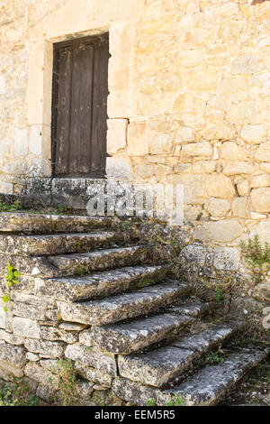 Old stone steps leading towards a wooden closed door Stock Photo