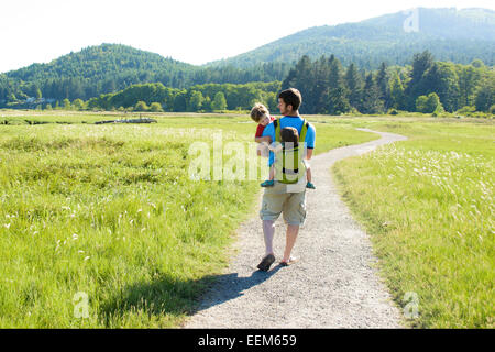 Father walking along a footpath carrying his son and daughter, USA Stock Photo