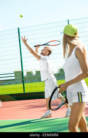 Young married couple playing tennis in white sportwear on the tennis court outside in the summer Stock Photo