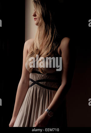 Young woman in elegant dress leaning against wall Stock Photo