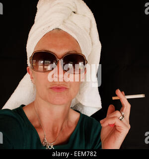 Portrait of woman wearing towel on head and sunglasses, holding cigarette Stock Photo
