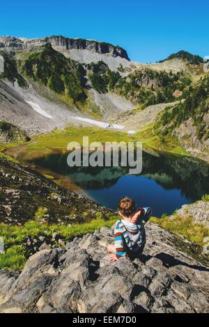 Girl throwing a rock into an alpine lake, USA Stock Photo