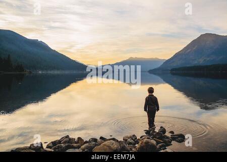 Boy standing on a rock by the edge of a lake, USA Stock Photo
