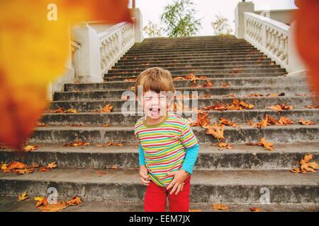 Boy (2-3) laughing after throwing leaves at camera Stock Photo