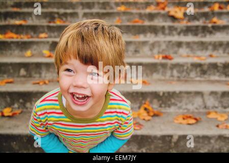 Portrait of a happy boy standing on steps laughing, USA