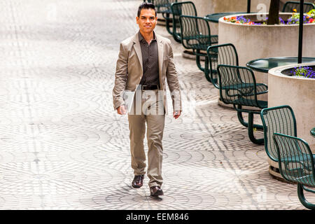 Hispanic businessman walking in courtyard Stock Photo