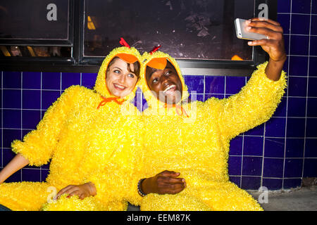 Couple taking cell phone selfies wearing chicken costumes Stock Photo