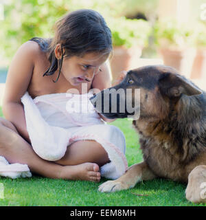 Girl wrapped in a towel sitting on grass next to her dog Stock Photo