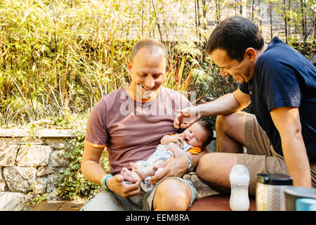 Caucasian gay couple admiring baby boy in backyard Stock Photo