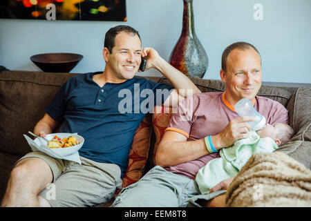 Caucasian gay couple relaxing with baby boy on sofa Stock Photo