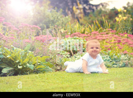 Baby girl (6-11 months) starting to crawl in park Stock Photo