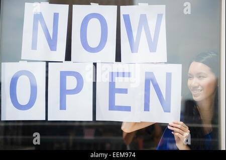 Woman hanging now open sign in store window Stock Photo