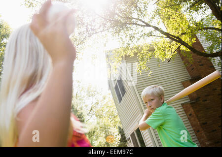 Caucasian children playing baseball in backyard Stock Photo