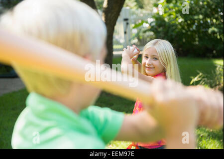 Caucasian children playing baseball in backyard Stock Photo