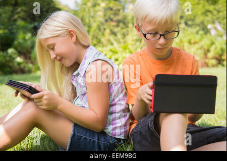 Caucasian children using digital tablets in backyard Stock Photo