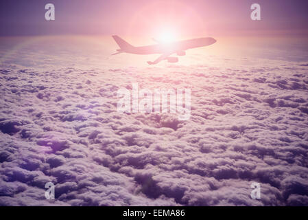 Silhouette of airplane flying over clouds Stock Photo