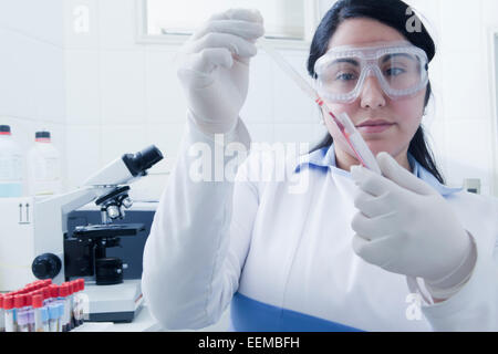 Hispanic scientist pipetting blood sample in laboratory Stock Photo