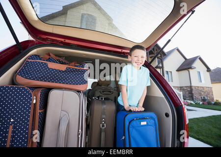 Caucasian boy smiling with suitcases in car Stock Photo
