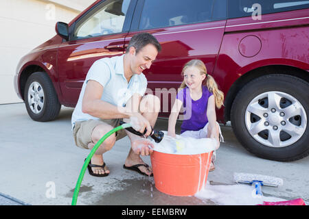 Caucasian father and daughter washing car in driveway Stock Photo