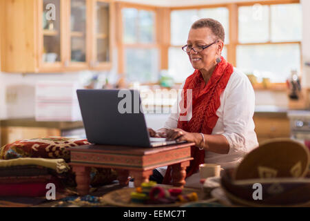 Older mixed race woman using laptop in home office Stock Photo