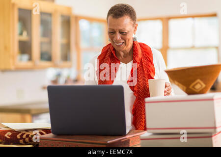 Older mixed race woman using laptop in home office Stock Photo