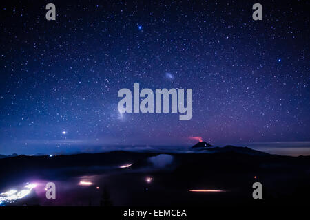 Starry night sky over active volcano Stock Photo