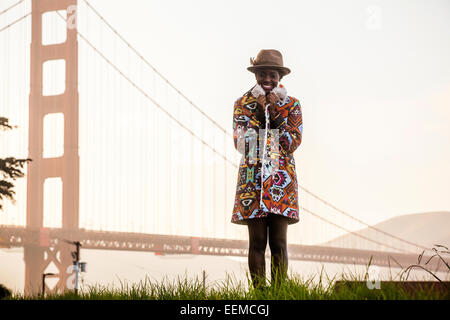 Black woman wearing colorful coat by Golden Gate Bridge, San Francisco, California, United States