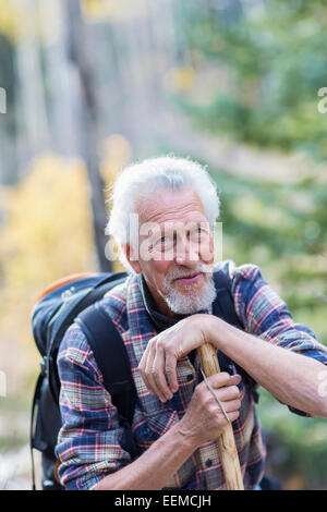 Caucasian hiker leaning on walking stick in forest Stock Photo