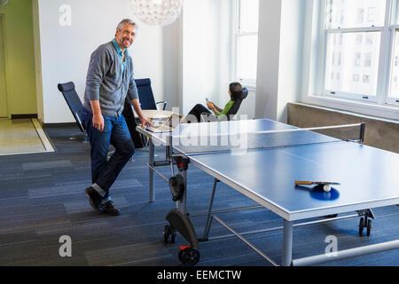 Businessman standing at table tennis table in office Stock Photo
