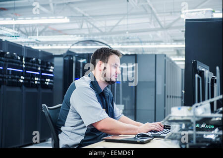 Caucasian technician using computer in server room Stock Photo