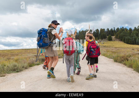 Caucasian hiker leading children on path in remote landscape Stock Photo
